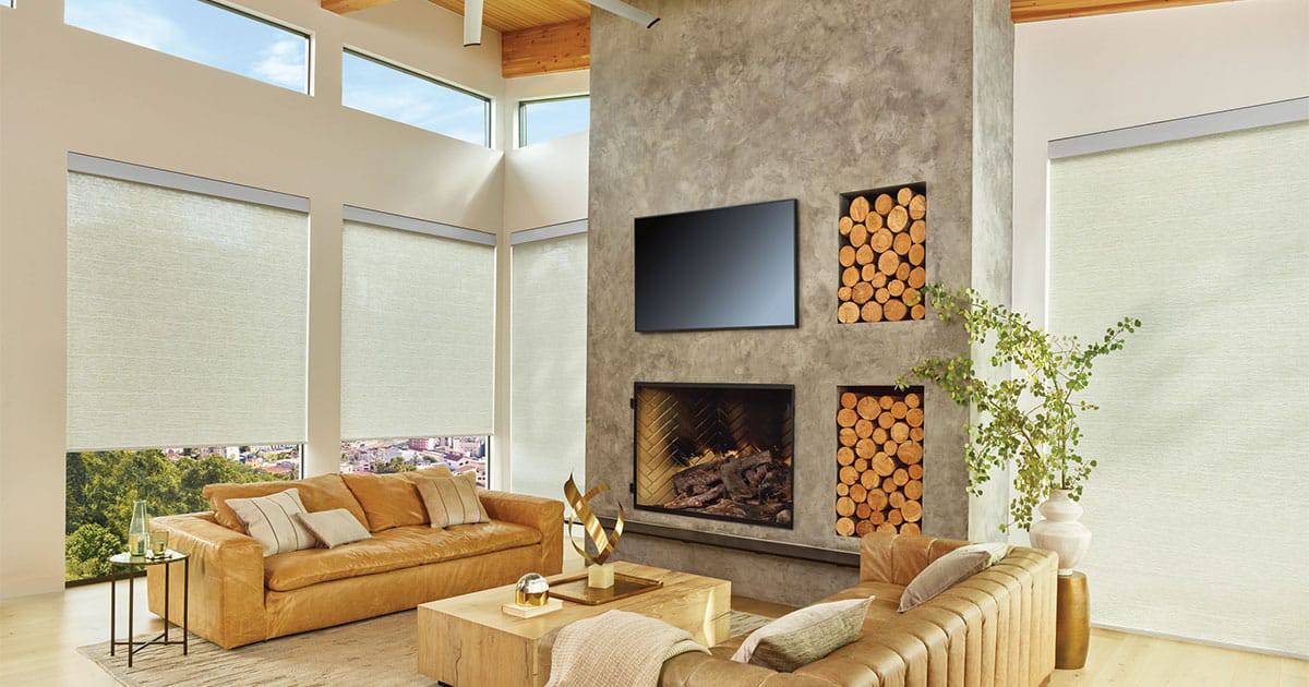 Luxurious living room with custom window blinds, neutral tones, modern fireplace, and wood accent features, highlighting premium window treatment solutions by Advance Blinds & Drapery.