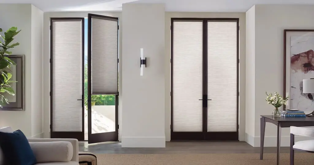 Sunset-colored roller shades on modern black window frames in a bright living room with white walls and minimalist decor.