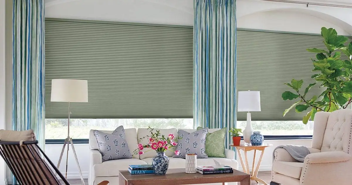 Soft green roller shades with sheer curtains and classic decor in a bright living room, enhancing window treatments and interior design aesthetics.