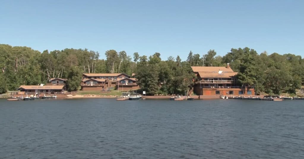 Lakefront homes with docks and boats on water, overlooking lush treed landscape, featuring modern window treatments and window covering solutions from Advance Blinds & Drapery.