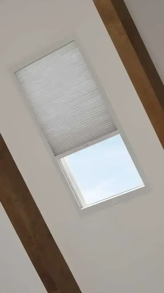 Blinds with a roller shade over a skylight window, providing modern window covering solutions for home or office. Custom blinds and drapery for interior design by Advance Blinds & Drapery.