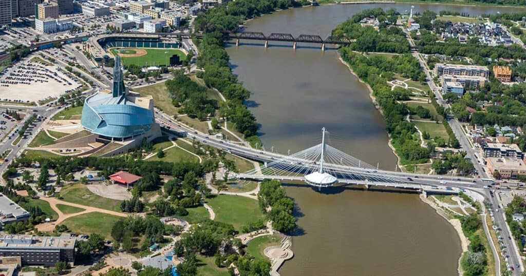 Modern city park with a bridge over a river, featuring lush green trees, walking paths, and cultural landmarks. Perfect for home and office window treatments in urban settings.