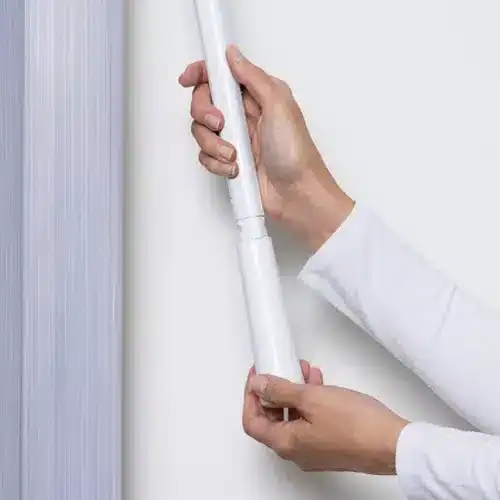 Modern white window blind being installed or adjusted, demonstrating professional window treatment services.