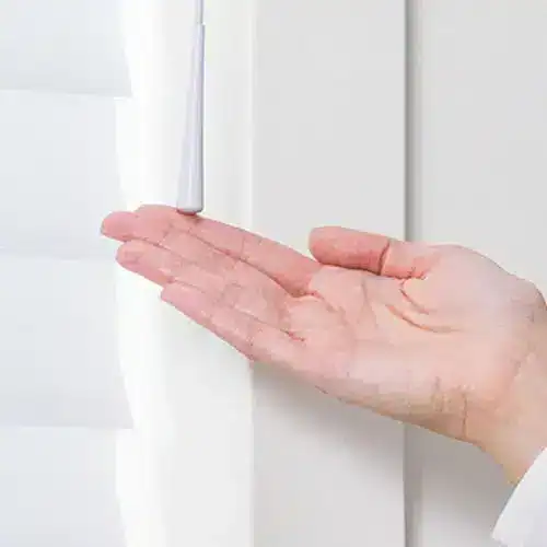 White window blinds being adjusted with a hand, showcasing custom blind solutions.