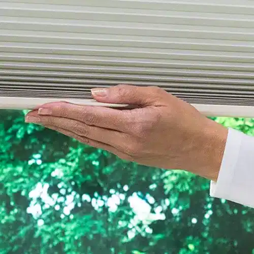 Smooth beige vertical blinds being gently cleaned or adjusted for optimal functionality.