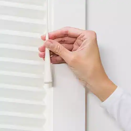 Smooth white window blinds being adjusted with a hand, showcasing quality window treatment solutions.