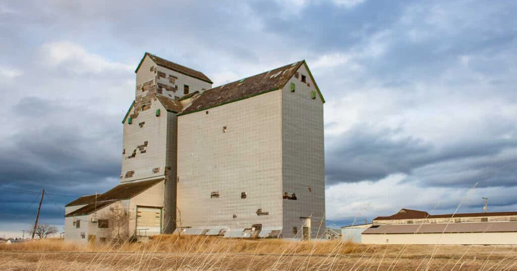 Rustic barn with tall silos on a rural farm, under a cloudy sky, showcasing agricultural architecture and countryside scenery.