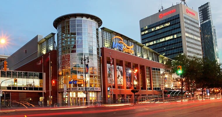 Modern commercial building with glass facades and illuminated signage, representing a shopping center in an urban area.